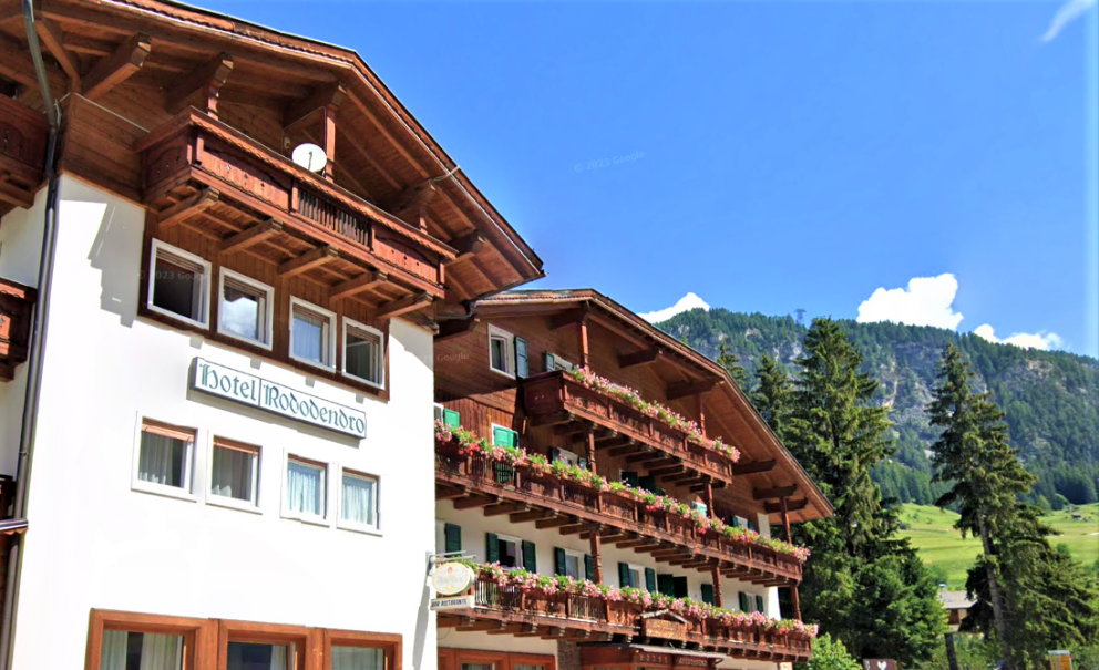 Hotel Rododendro in montagna, con balconi fioriti e vista panoramica.